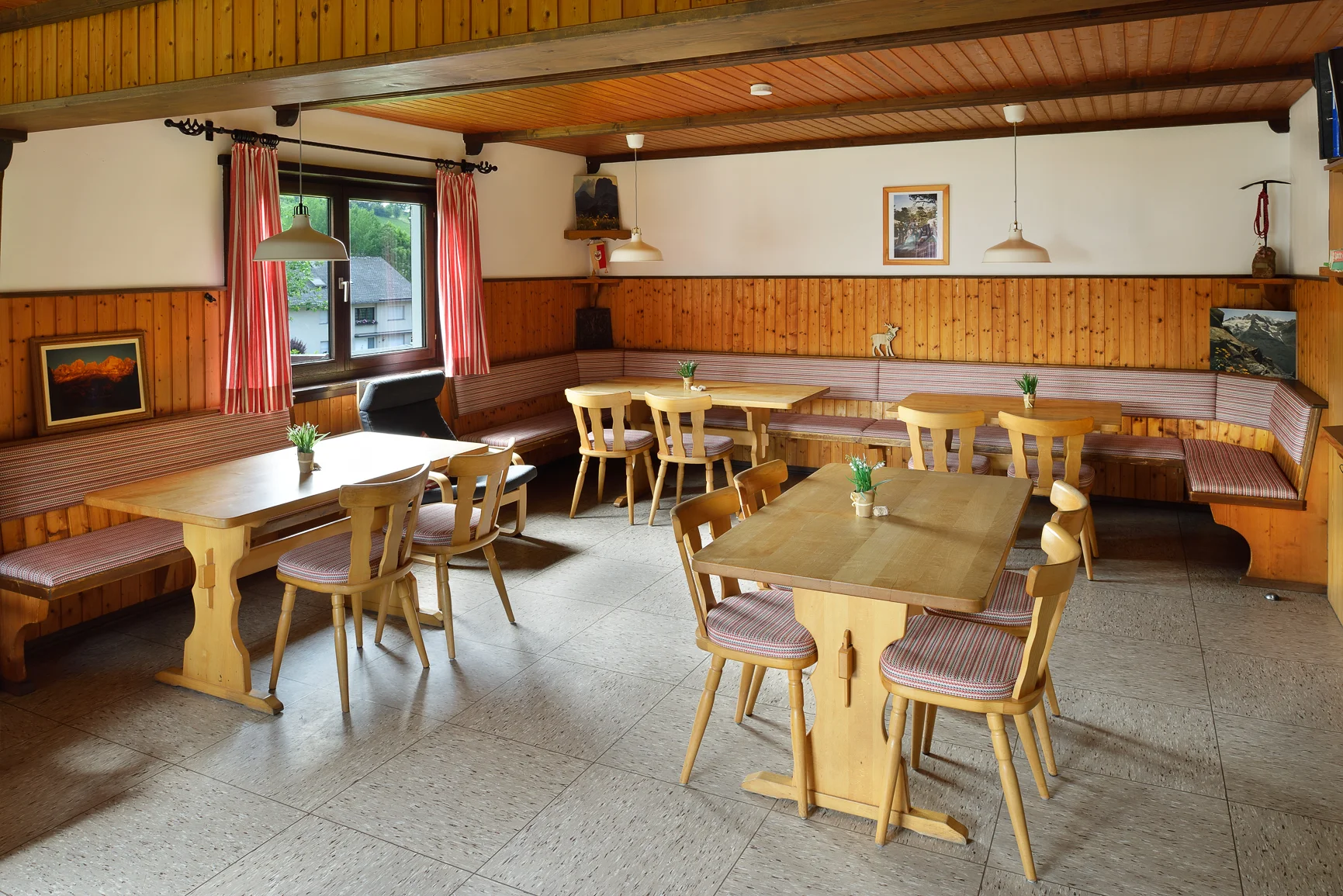 Ein traditioneller Gastraum mit Holzbänken an der Wand, Tischen und kleiner Dekoration. | © DAV Dortmund