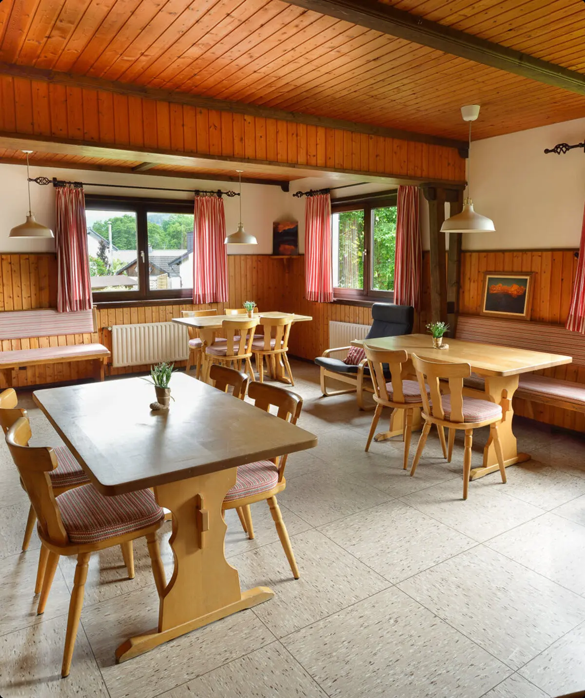 Ein heller Gastraum mit mehreren Tischen und Sitzbänken an den Fenstern, gemütlich eingerichtet. | © DAV Dortmund