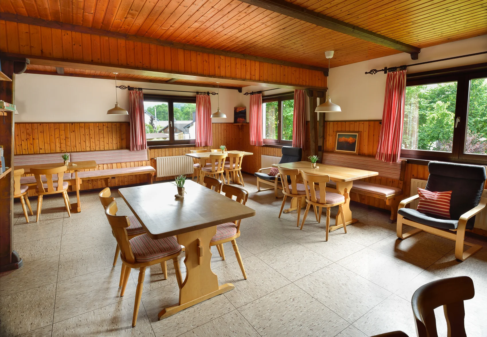 Ein heller Gastraum mit mehreren Tischen und Sitzbänken an den Fenstern, gemütlich eingerichtet. | © DAV Dortmund