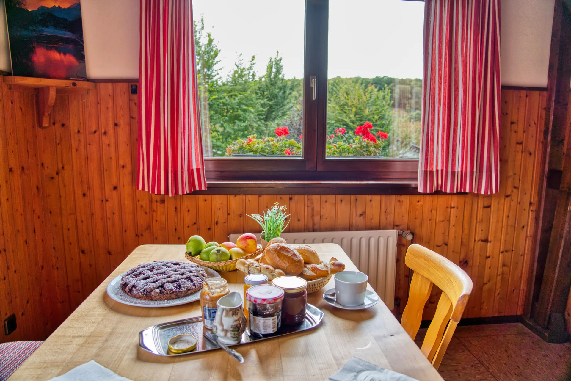 Ein gedeckter Frühstückstisch mit Marmelade, Brot und Obst vor einem Fenster mit Blumen. | © DAV Dortmund