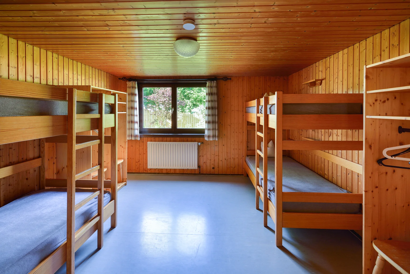 Ein heller Raum mit drei stabilen Etagenbetten aus Holz und Blick nach draußen. | © DAV Dortmund