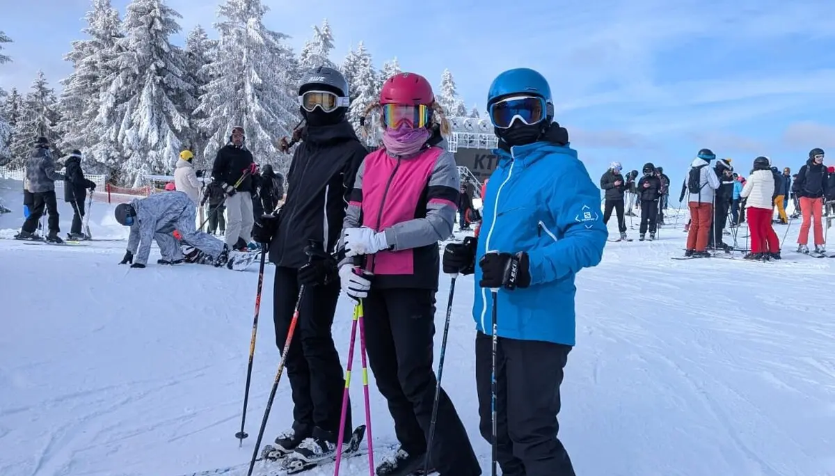 Drei Skifahrer*innen posieren mit Helm und Skistöcken vor winterlicher Kulisse. | © DAV Dortmund