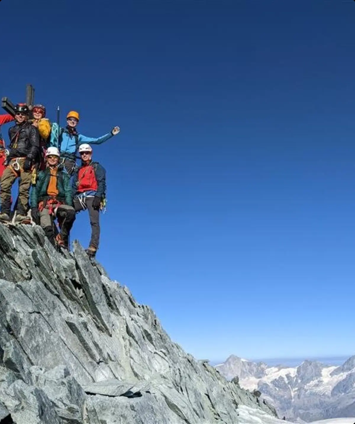     Sechs Bergsteiger*innen jubeln auf einem felsigen Gipfel mit Gletschern im Hintergrund. | © jdav nrw