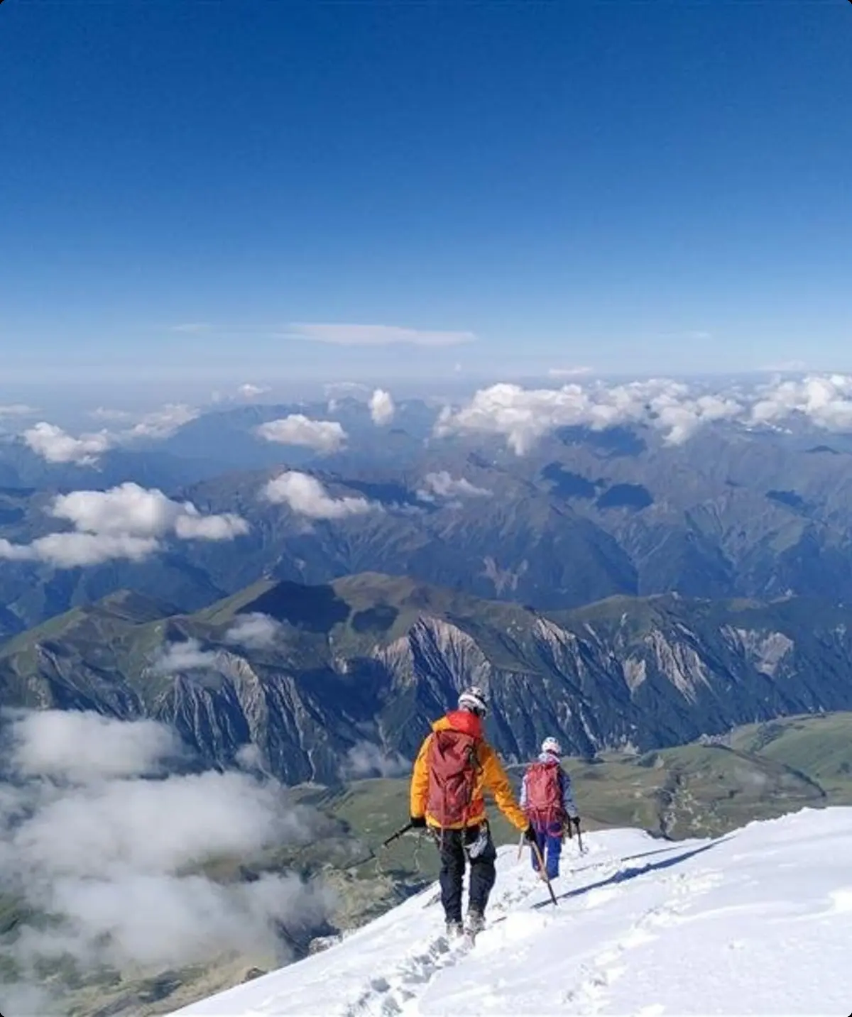 Zwei Bergsteiger*innen auf einem Schneefeld mit weitem Blick über ein Gebirge. | © jdav nrw
