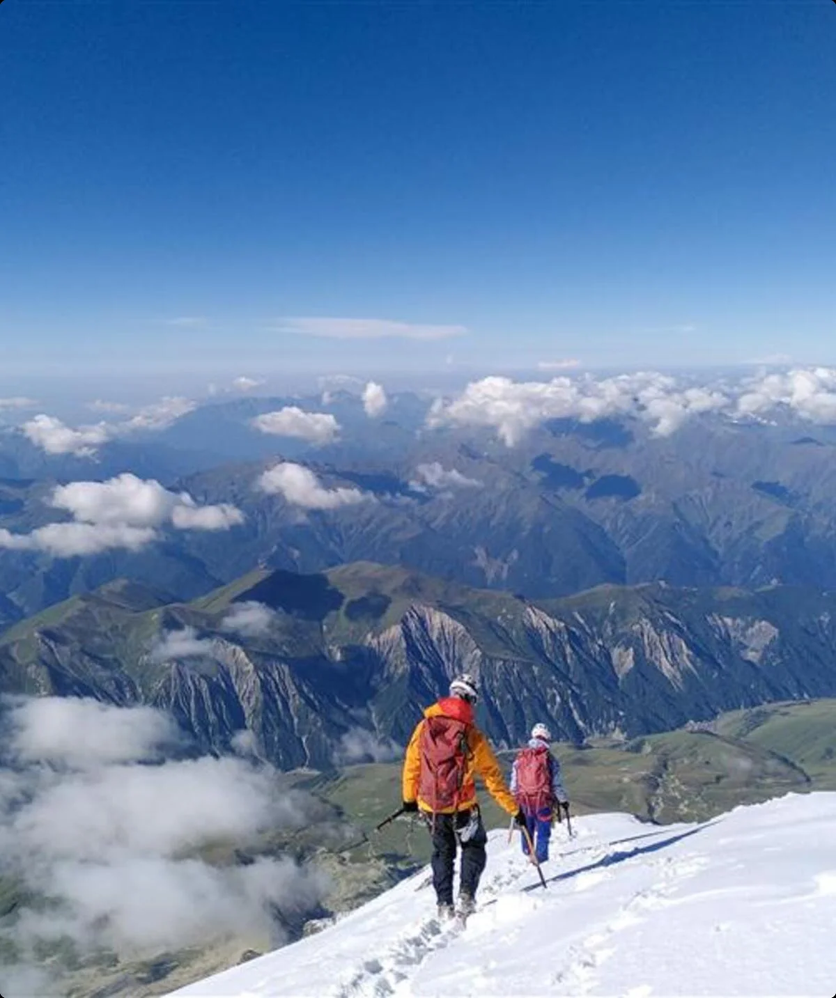 Zwei Bergsteiger*innen auf einem Schneefeld mit weitem Blick über ein Gebirge. | © jdav nrw
