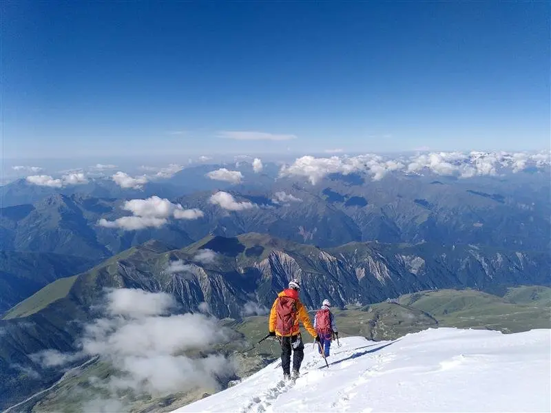 Zwei Bergsteiger*innen auf einem Schneefeld mit weitem Blick über ein Gebirge. | © jdav nrw