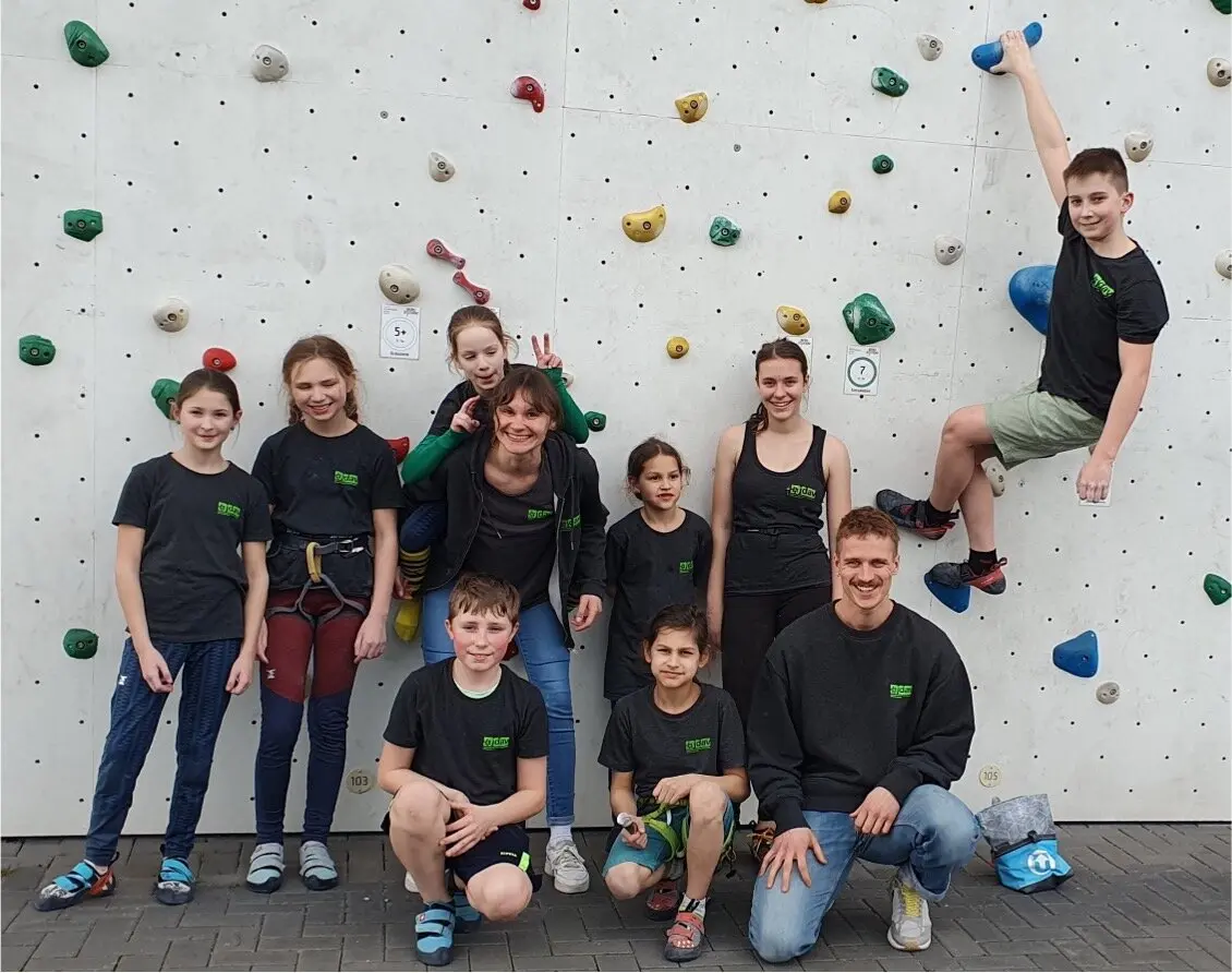 Kinder und Jugendliche in DAV-Shirts stehen vor einer Außen-Kletterwand mit bunten Griffen. | © DAV Dortmund