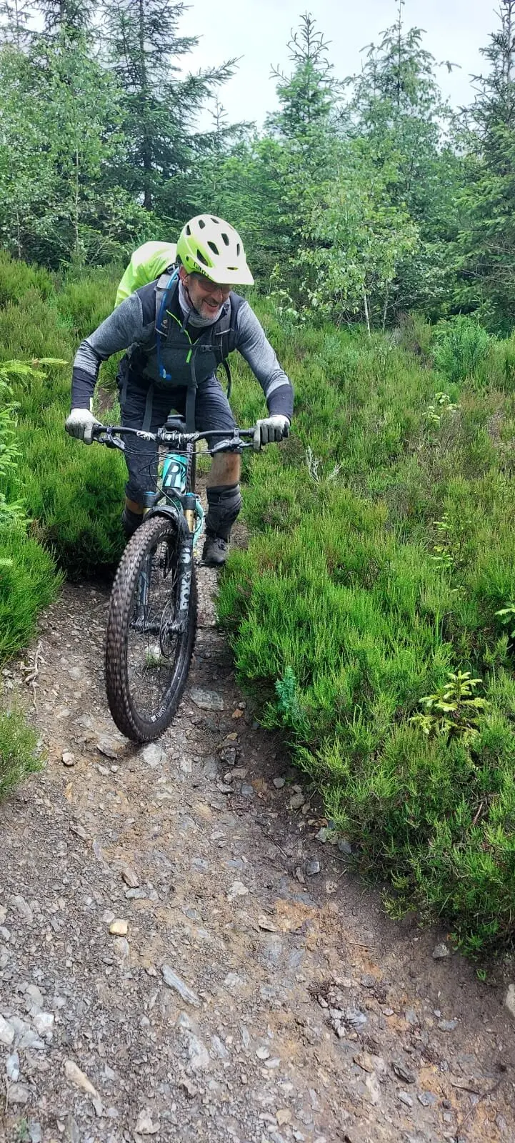 Mountainbiker fährt einen schmalen Pfad durch grüne Büsche bergab. | © Maik Gniazdowski